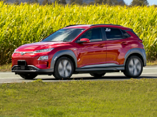 Electric cars plugged in charging in front of solar panels and wind turbines